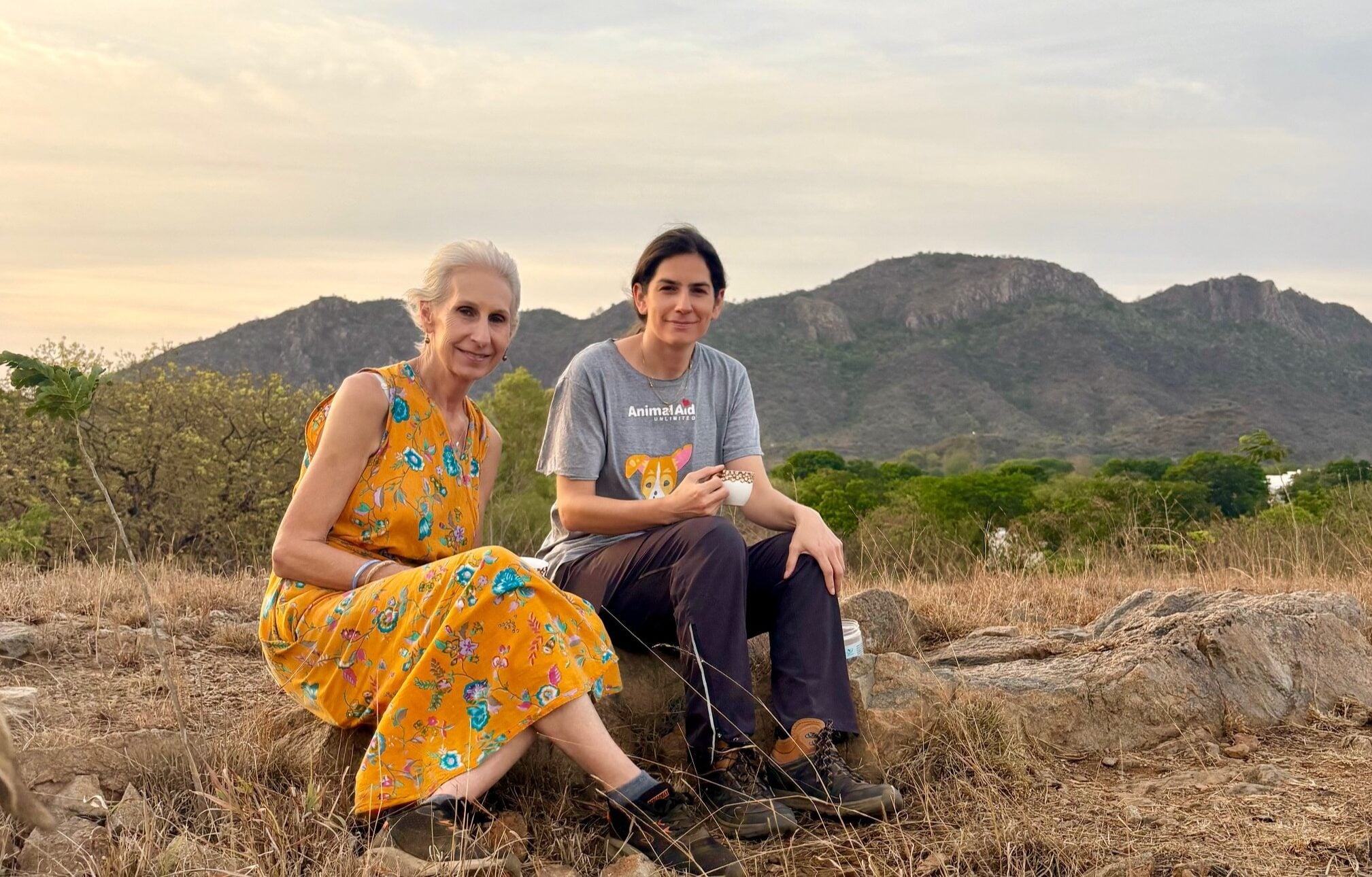 Photo of Erika and Claire sitting on a rock at sunrise