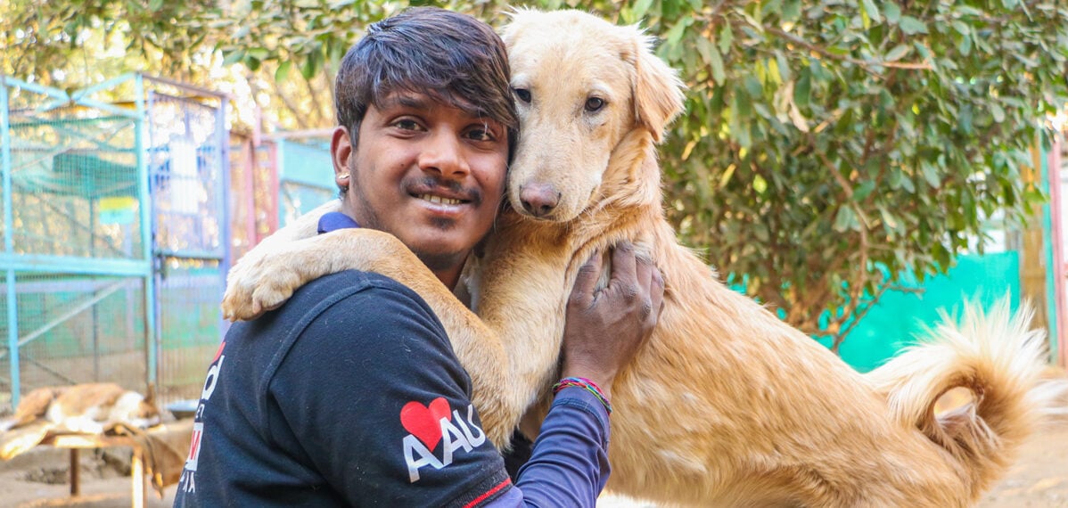 Golden dog hugging an Indian man over the shoulders